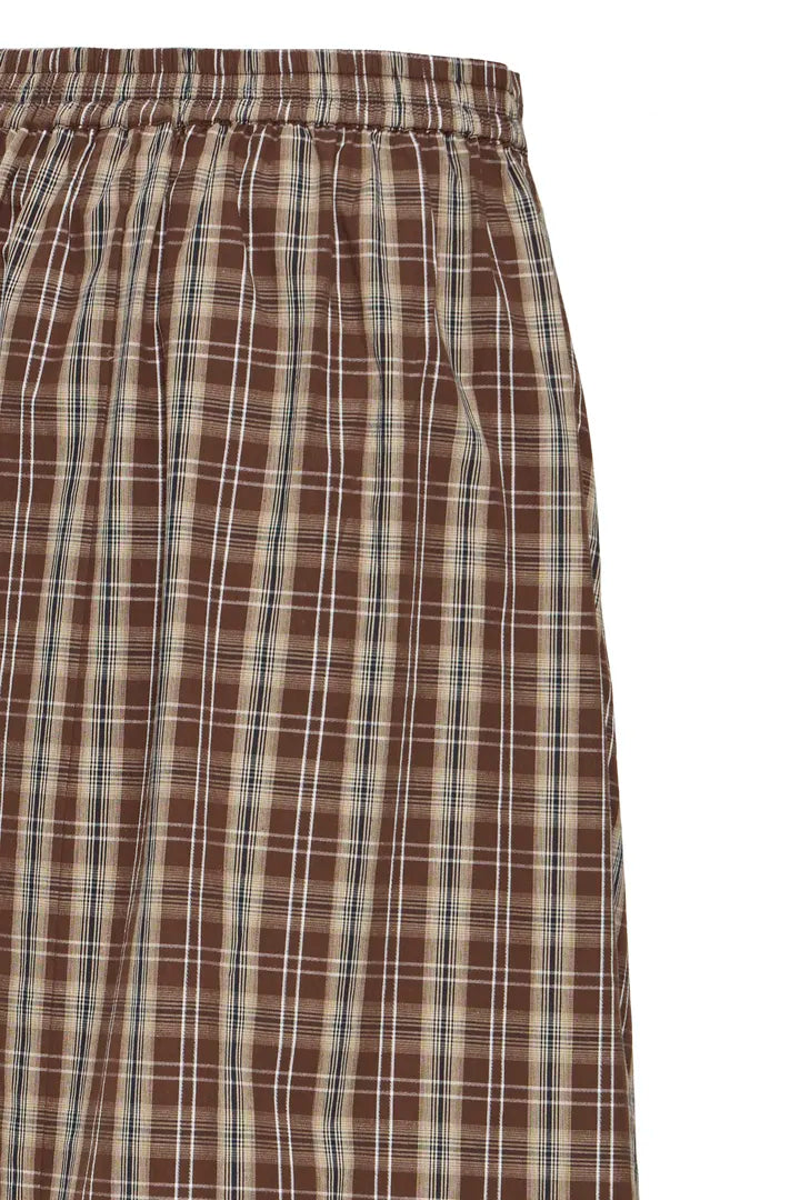 Close-up of a brown plaid garment with an elastic waistband, featuring intersecting white and thin blue grid lines on a plain white background.