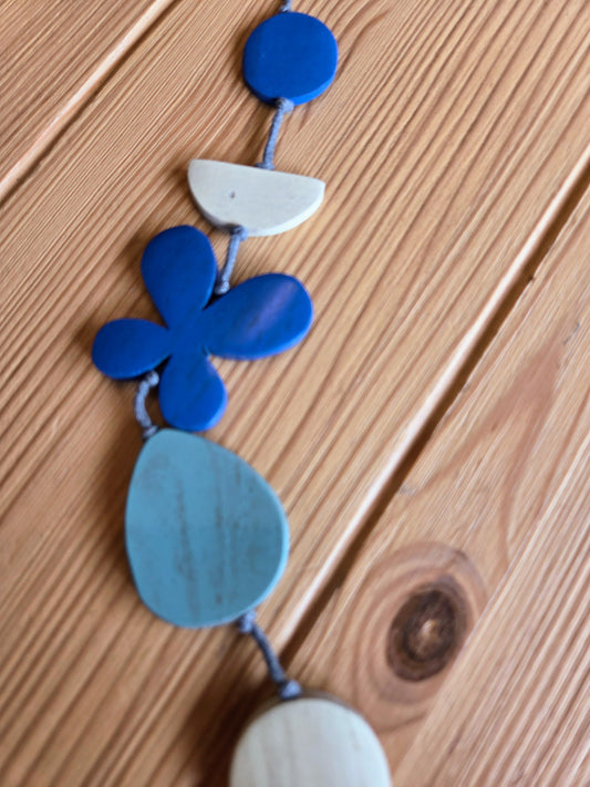 Necklace with blue and white geometric pendants on a wooden surface