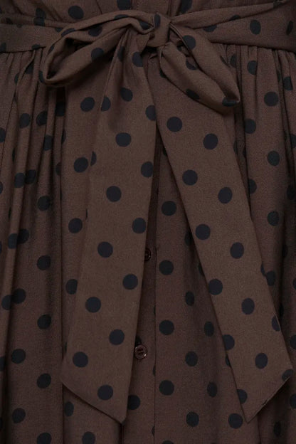 Close-up of a brown fabric garment with dark navy polka dots and a matching tie belt.