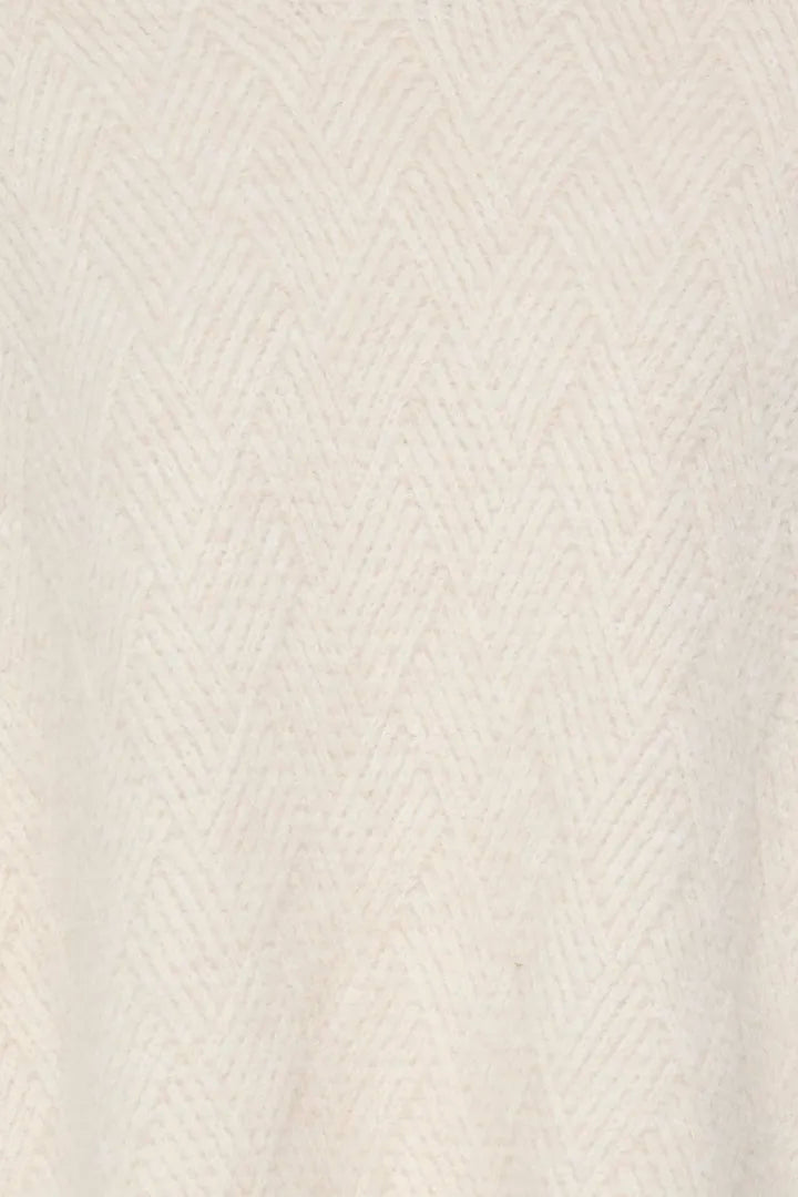 Close-up of a cream-colored knit fabric with a subtle herringbone pattern.