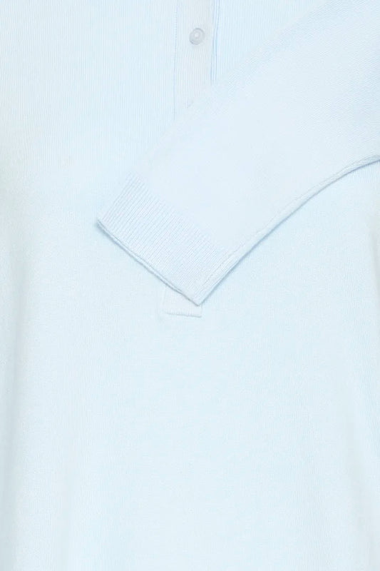 Close-up of a light blue ribbed knit polo shirt showing the collar and button placket.