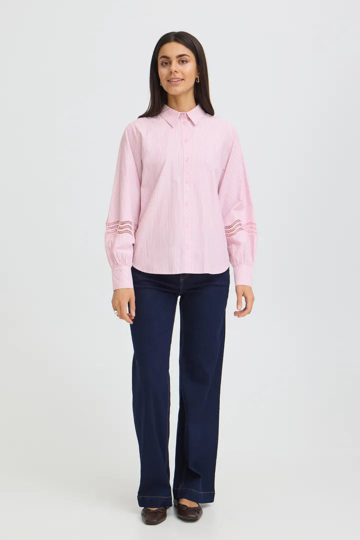 Woman wearing a pink shirt and dark blue jeans on a white background