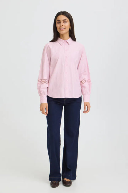 Woman wearing a pink shirt and dark blue jeans on a white background
