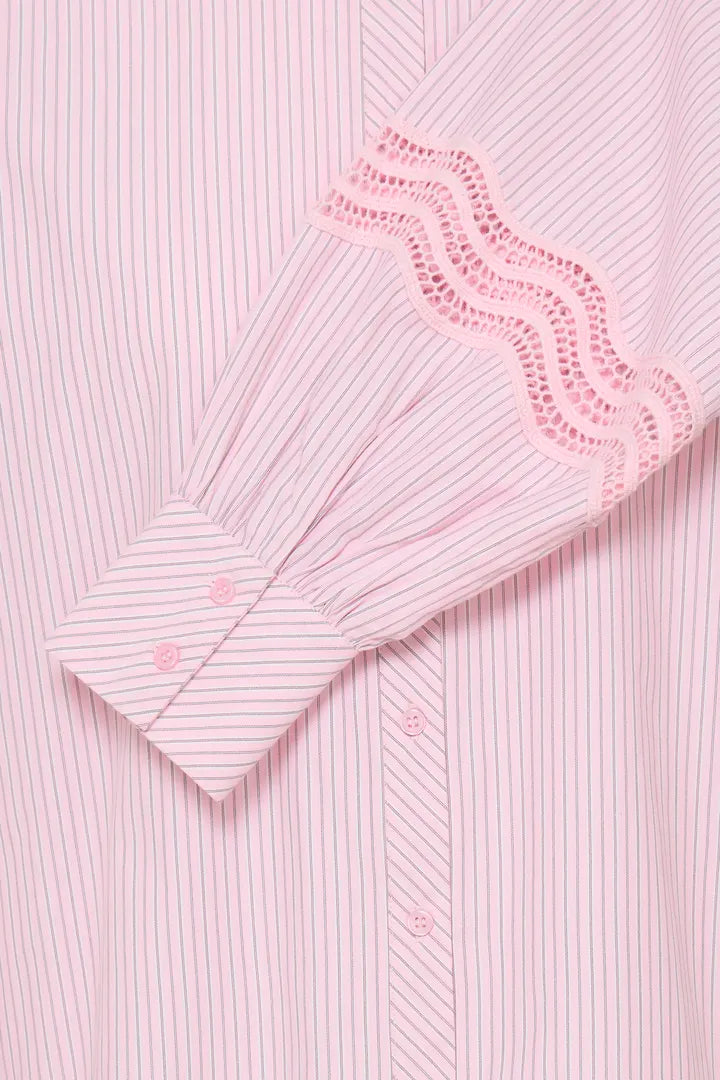 Close-up of a light pink and white striped shirt with a decorative eyelet lace cuff on the sleeve.