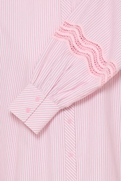 Close-up of a light pink and white striped shirt with a decorative eyelet lace cuff on the sleeve.