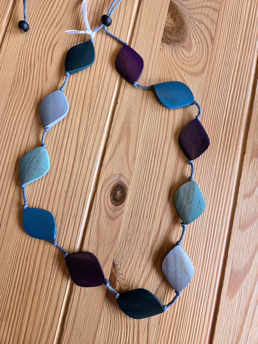 Necklace with blue and purple beads on a wooden surface