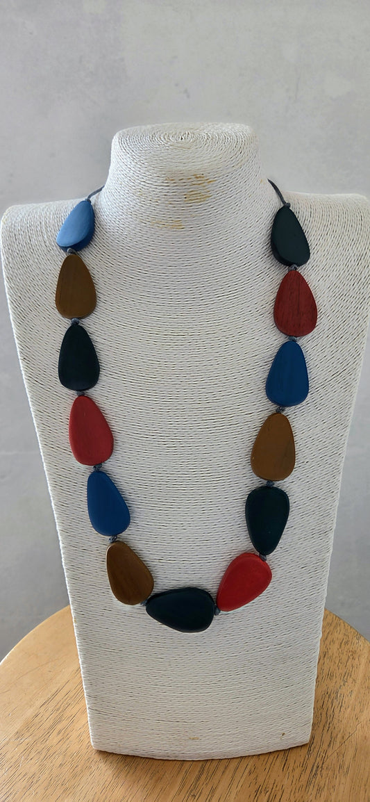 Necklace with colorful teardrop-shaped beads on a white bust against a gray background