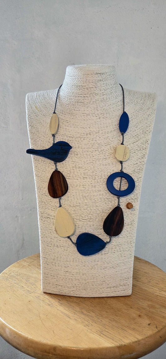 Necklace with blue, brown, and beige beads on a wooden stand against a gray background