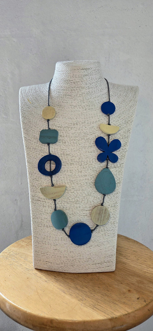 Necklace with blue and beige beads on a wooden stand against a gray background