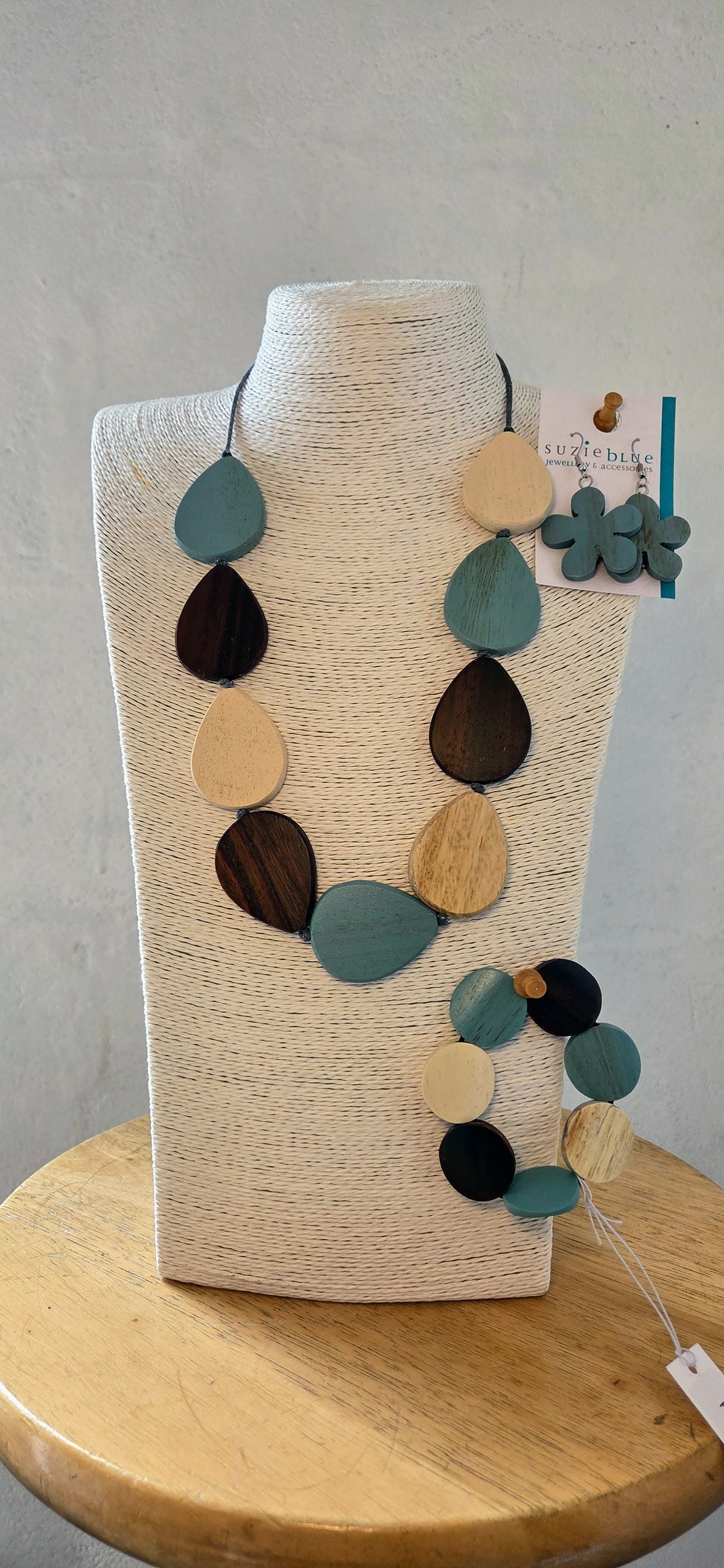 Necklace with multicolored teardrop pendants on a mannequin bust against a gray background.