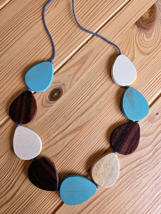 Necklace with teardrop-shaped beads in various blue colours on a wooden surface