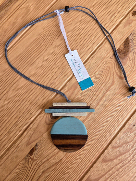 Necklace with colourful pendant on a wooden mannequin bust against wood background