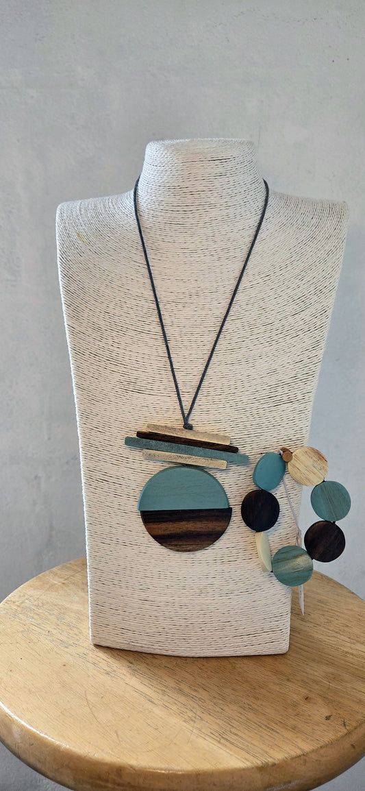 Necklace with colourful pendant on a wooden mannequin bust against a gray background
